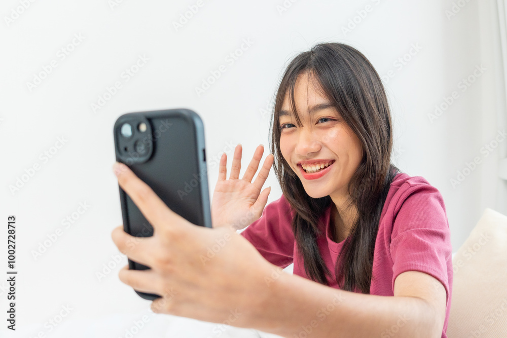 Asian young woman using mobile phone virtual video call remotely in house. Teenager girl sitting on bed and using smartphone communicating online in bedroom. Technology device concept Asian young woman using mobile phone virtual video call remotely in house. Teenager girl sitting on bed and using smartphone communicating online in bedroom. Technology device concept