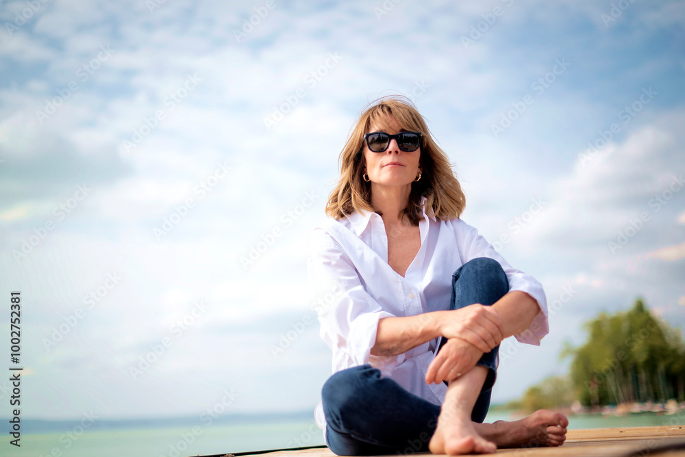 Full length of a blond haired woman relaxing by the lake Full length of a blond haired woman relaxing by the lake