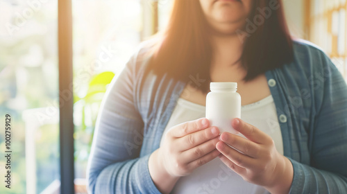 Determined overweight woman holding weight-loss pill bottle, focused on achieving health goals. Soft, minimalist background with ample copy space. Concept of diet, determination, and healthy living. photo