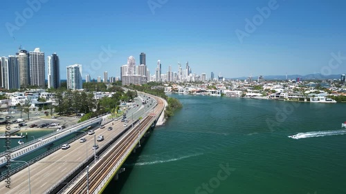 Commuter traffic enters a towering urban city skyline across a bridge over a coastal body of water. Gold Coast Australia photo