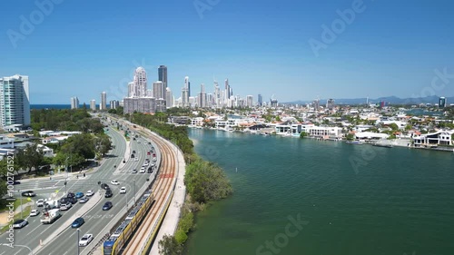 Modern electric tram travels across towards the towering skyline of Surfers Paradise Gold Coast Queensland. Drone view photo