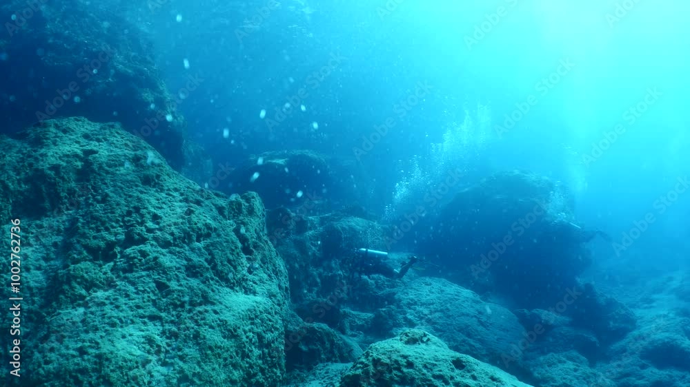 scuba divers exploring around a reef underwater deep blue water big rocks and bubbles ocean scenery scuba divers exploring around a reef underwater deep blue water big rocks and bubbles ocean scenery