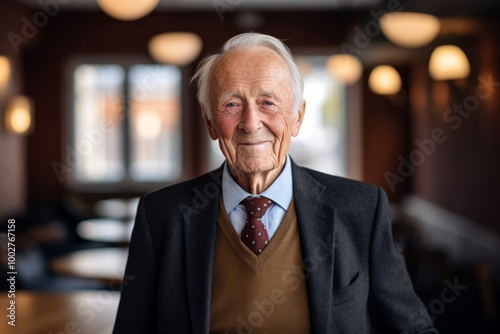 Portrait of a smiling elderly man in his 90s wearing a professional suit jacket isolated in scandinavian-style interior background