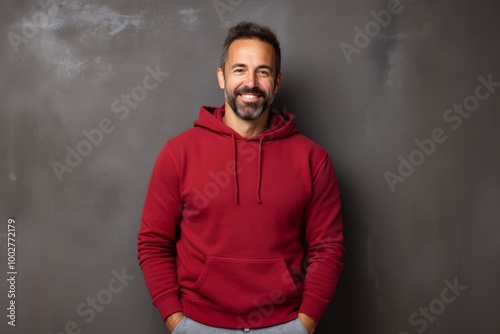 Portrait of a smiling man in his 40s wearing a thermal fleece pullover isolated on bare concrete or plaster wall