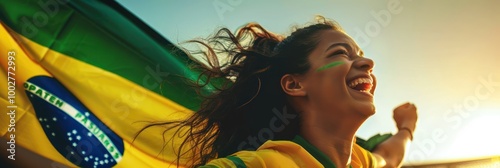 Vibrant yellow shirt clad young woman radiates joy in a moment of celebration, holding a Brazilian flag against a simple gray background, ideal for editorial or high-end use. photo