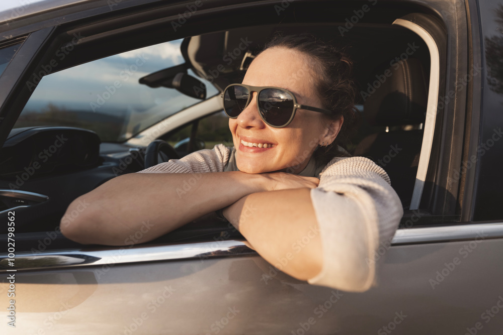 Happy young woman drivier looking out of car window, auto travel and adventure