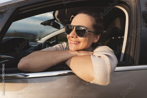 Obraz na płótnie Happy young woman drivier looking out of car window, auto travel and adventure w salonie