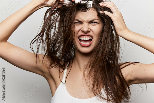 Frustrated woman with messy hair expressing stress and tension in a simple studio setting Her facial expression shows emotion, with a neutral background enhancing the focus on her photo