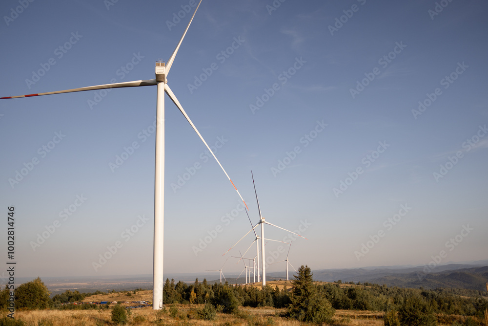Obraz premium Wind turbines in a scenic, mountainous landscape, harnessing renewable energy from the wind, symbolizing sustainability and eco-friendly technology