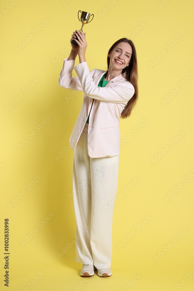 Happy winner with gold trophy cup on yellow background Happy winner with gold trophy cup on yellow background