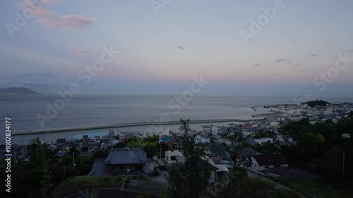 Sunset glow in sky over quiet harbor and small coastal town of Iwaya 