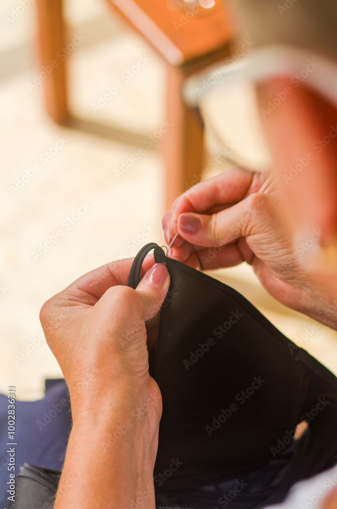 The hands of a senior woman who uses needle and thread to repair a black garment. High quality photo The hands of a senior woman who uses needle and thread to repair a black garment. High quality photo
