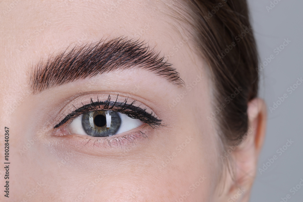 Naklejka premium Woman after brow lamination procedure on grey background, closeup
