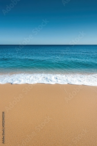 Beach view with golden sand and clear blue water under a bright sky.