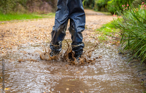 Child in welly boots, jump, jumping in mud.