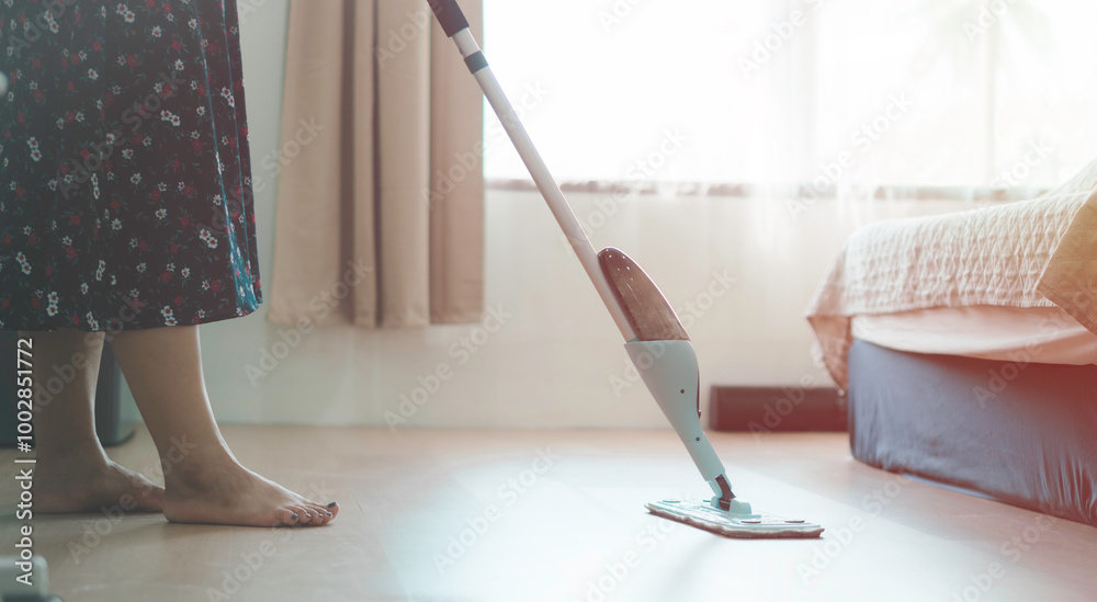 A woman is cleaning a floor with a mop. a woman taking care of her home