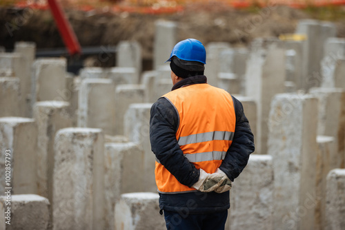 Construction site, pile foundation. Worker standing in front of concrete pile foundation.  photo