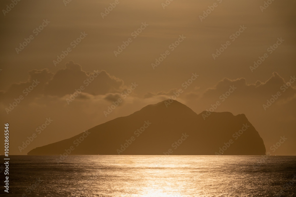 A serene night scene of the ocean with gentle waves, featuring a mesmerizing moonrise behind the iconic Turtle Island, Yilan, Taiwan. The moon gracefully dances through the clouds. A serene night scene of the ocean with gentle waves, featuring a mesmerizing moonrise behind the iconic Turtle Island, Yilan, Taiwan. The moon gracefully dances through the clouds.