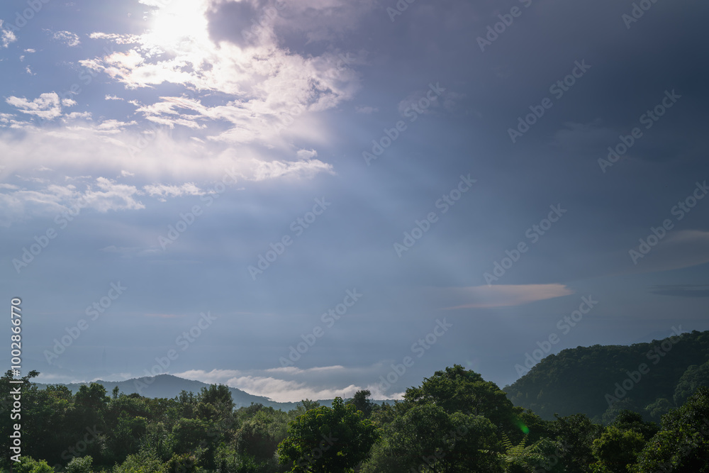 Fototapeta premium A breathtaking panoramic view of a Taipei city skyline partially veiled by clouds. Golden sunbeams pierce through the overcast sky, casting a warm glow on the urban landscape. Taiwan.