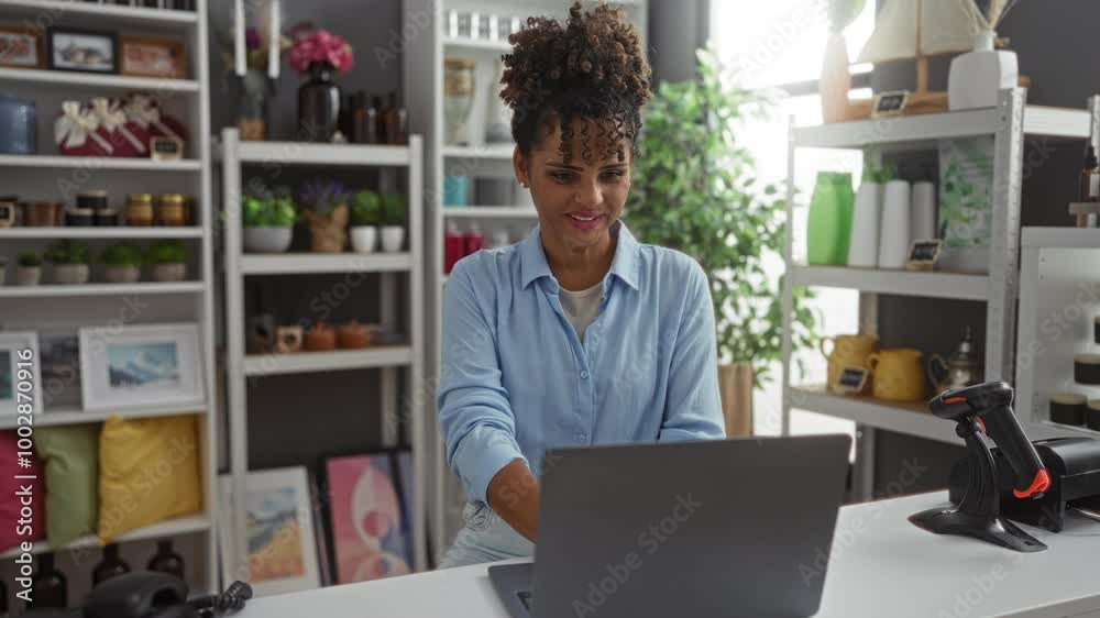 Young woman celebrates with closed fists while working on a laptop in a beautifully decorated home decor store, surrounded by plants and colorful decoration items on shelves. Young woman celebrates with closed fists while working on a laptop in a beautifully decorated home decor store, surrounded by plants and colorful decoration items on shelves.