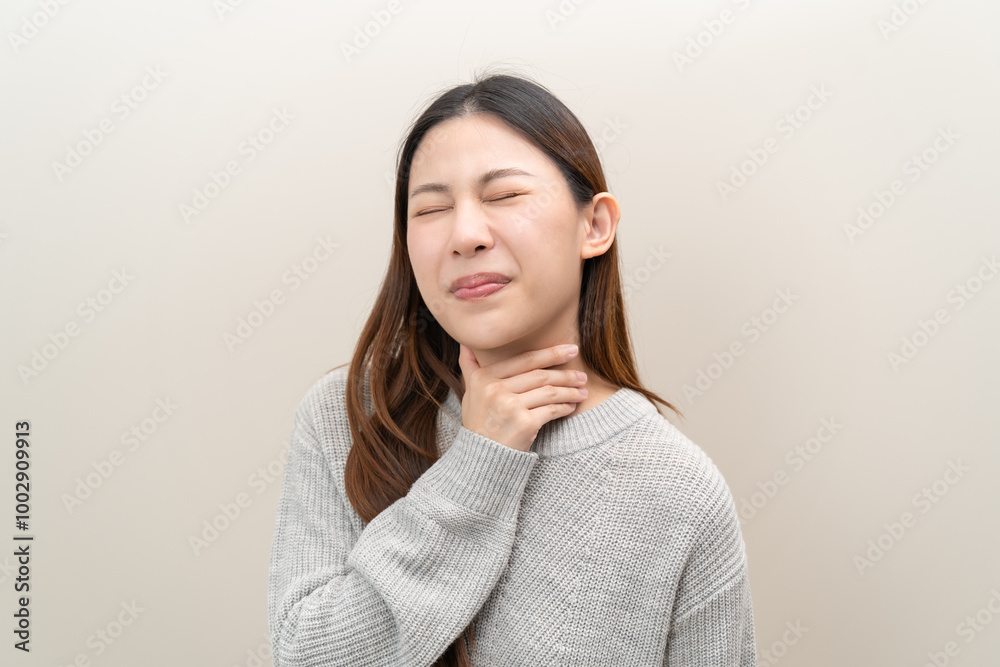 Sore throat in flu season. Young asian woman touching her neck and feeling pain in throat in the bedroom at home. Sore throat in flu season. Young asian woman touching her neck and feeling pain in throat in the bedroom at home.