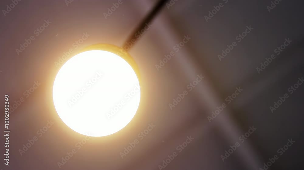 Zooming In on a Round Ceiling Lamp as It Lights Up in a Room - 4K Resolution