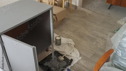 Process of redesigning an old wooden nightstand. A woman sands off the old paint, preparing the surface for a furniture makeover. Perfect for DIY, home improvement, and furniture restoration themes