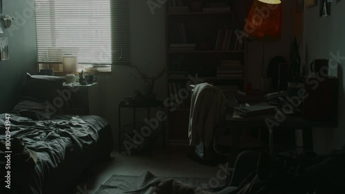 No people tilt up view of untidy dark room with unmade bed, wrinkled carpet and record player on it, messy desk and scattered clothes