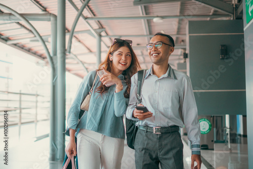 A joyful and cheerful couple strolls hand in hand together at a modern and contemporary airport