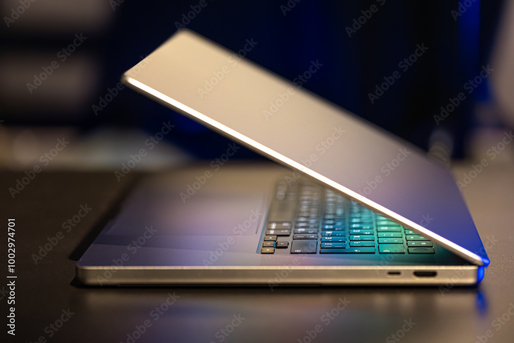 A laptop computer with a half-open screen on a dark background. A laptop computer with a half-open screen on a dark background.