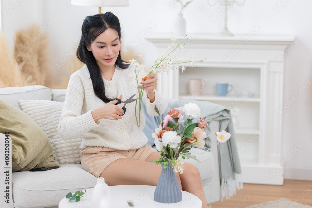 Young asian woman arrange flowers in a vase in a living room Young asian woman arrange flowers in a vase in a living room