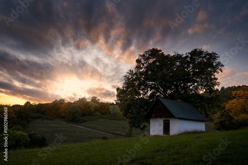 Autumn sunset landscape. Fall scenery with colored sky, trees and leafs. Country chalet near Banska Bystrica in central Slovakia