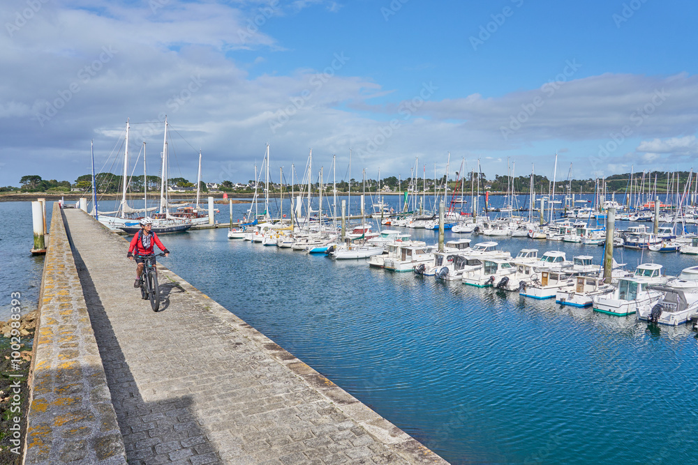 Obraz premium nice senior woman cycling with her electric mountain bike Aber Wrach harbour in Brittany, France