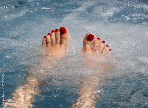 feet of woman with red painted toenails are soaking in a pool during a hydrotherapy session to improve blood circulation photo