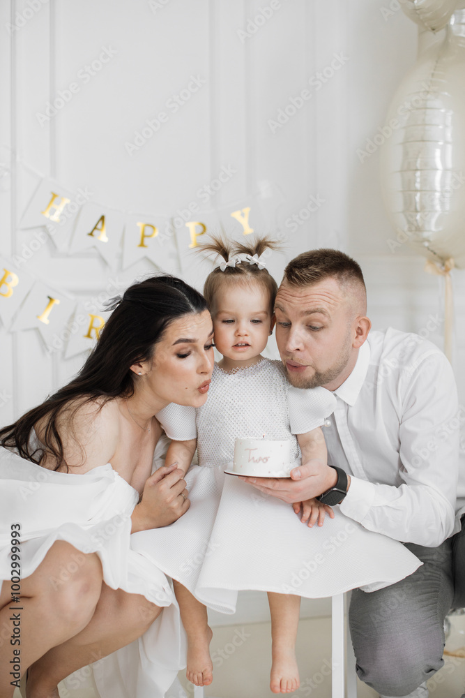 Caucasian mother, father, and young daughter celebrating girl's second birthday with cake. Family gathered together creating joyful and loving atmosphere. Caucasian mother, father, and young daughter celebrating girl's second birthday with cake. Family gathered together creating joyful and loving atmosphere.