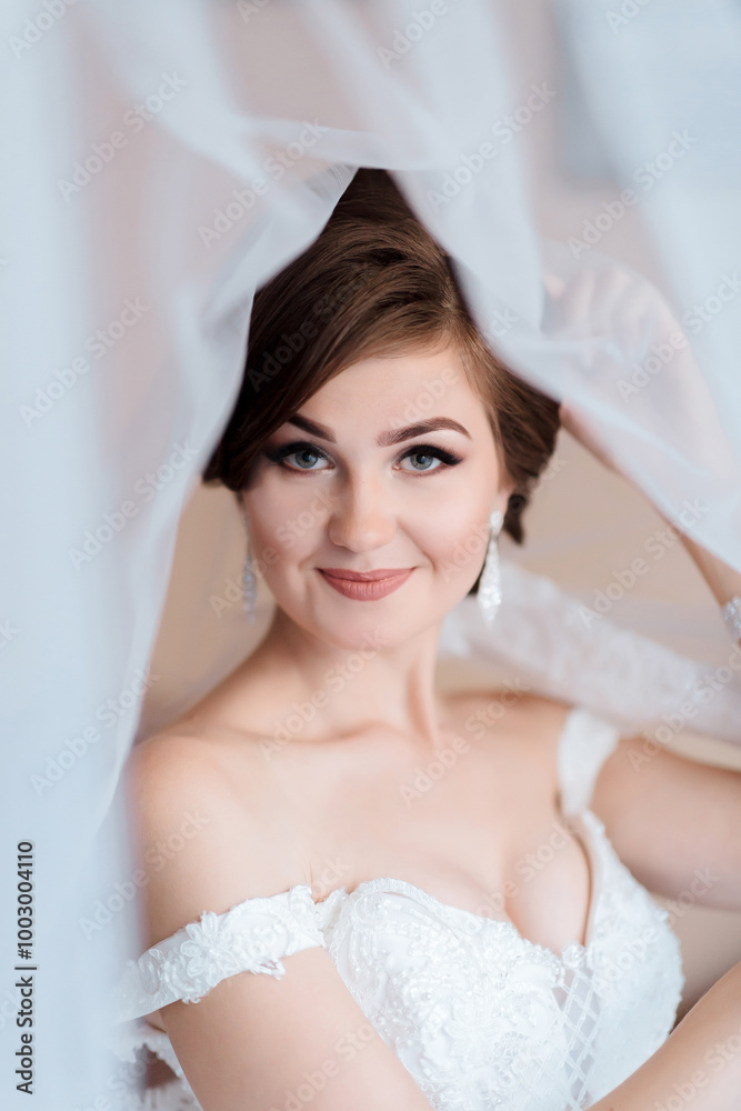 A woman is posing for a picture with her hand behind her back. She is wearing a white dress and has her hair in a bun. The image has a soft and romantic mood, with the woman's smile A woman is posing for a picture with her hand behind her back. She is wearing a white dress and has her hair in a bun. The image has a soft and romantic mood, with the woman's smile