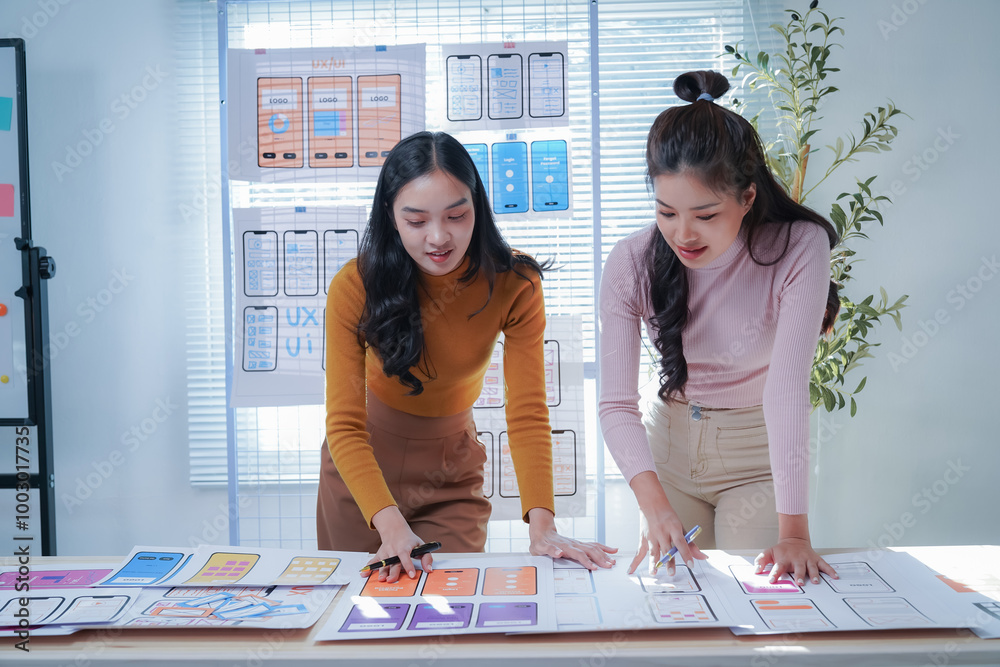 Two female ui/ux designers are working together in their office ...