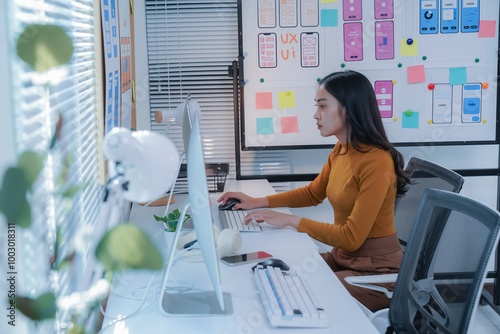 Focused asian woman designs user-friendly apps in a creative. Professional office setting. Embodying modern web design. She navigates software development with strategic planning and agile expertise