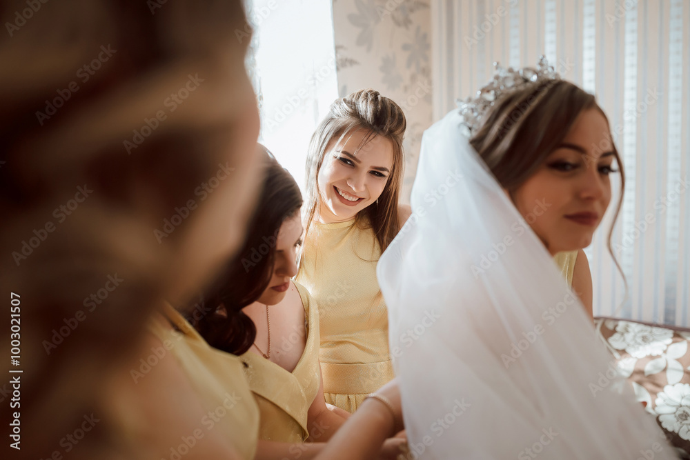 Naklejka premium A group of women are getting ready for a wedding. One of the women is wearing a white veil and is smiling