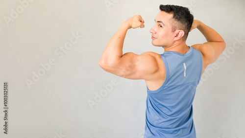 Young athletic man posing in sportswear and flexing his muscles in a studio