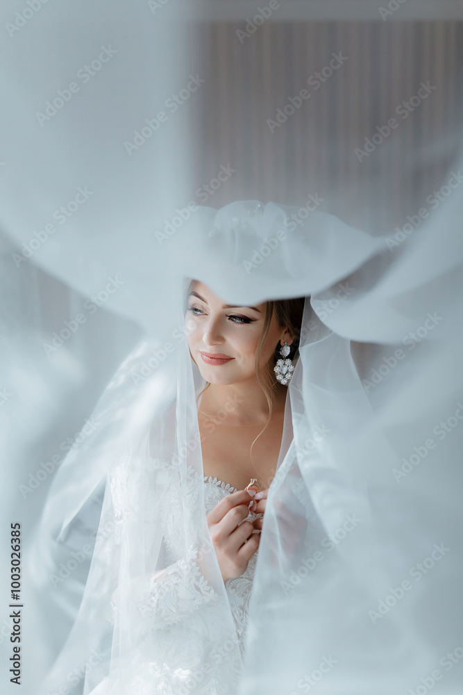 A bride is standing in front of a curtain, with her veil covering her face. She is wearing a white dress and a necklace A bride is standing in front of a curtain, with her veil covering her face. She is wearing a white dress and a necklace