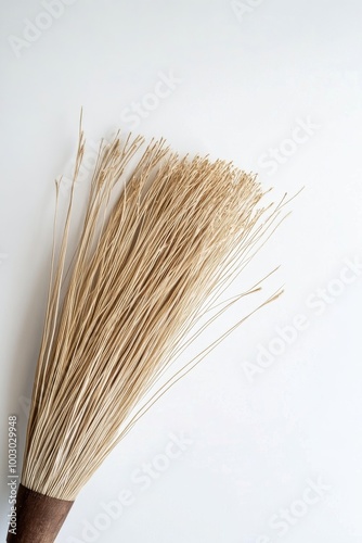 Natural straw broom displayed on a clean white background for decorative or p...