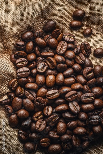 A rustic display of freshly roasted coffee beans on a textured burlap fabric ...