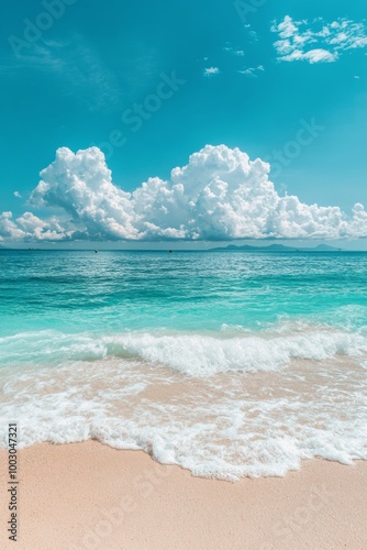 Tranquil beach with gentle waves and fluffy clouds under a bright blue sky on...