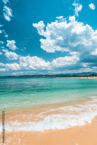 Tranquil beach with gentle waves and fluffy clouds under a bright blue sky on...