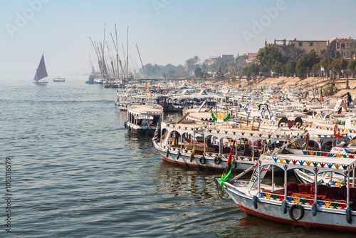 Luxor, Egypt - 9 February 2022: Tourist boats at pier on the east bank of the Nile, Luxor, Egypt. Luxor and the ruins of the temple complexes in Karnak - the largest open-air museum in the world photo