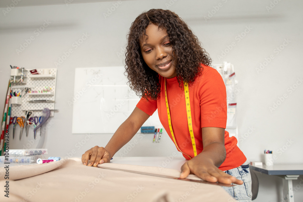 Dressmaker in orange tshirt tailoring fabric for a new dress Dressmaker in orange tshirt tailoring fabric for a new dress