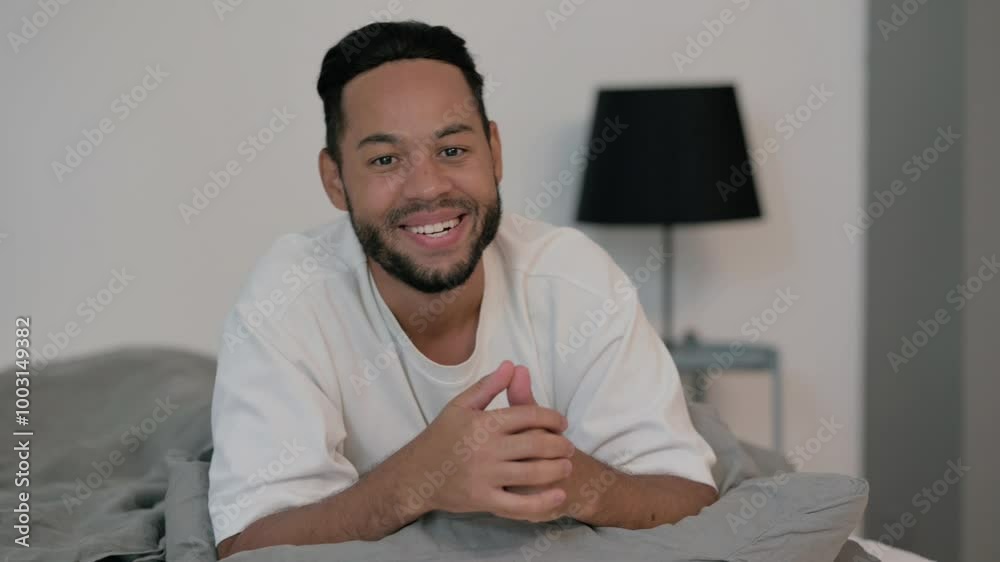 Young Man Doing video Chat while Lying on Stomach in Bed