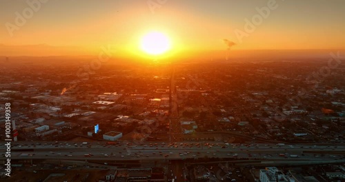 Transport moving by the highways of Los Angeles, California, USA. Metropolis cityscape dazzled by the orange light of sunset. Top view.