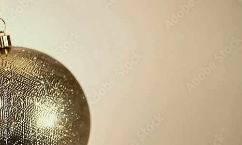 Sparkling big gold Christmas ball with intricate patterns spins slowly against a beige minimalist background, open space, new year